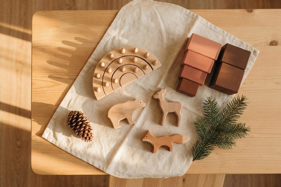 Nachhaltiges Holzspielzeug auf Holztisch — Waldtiere, Regenbogen-Stecker und Holzbausteine